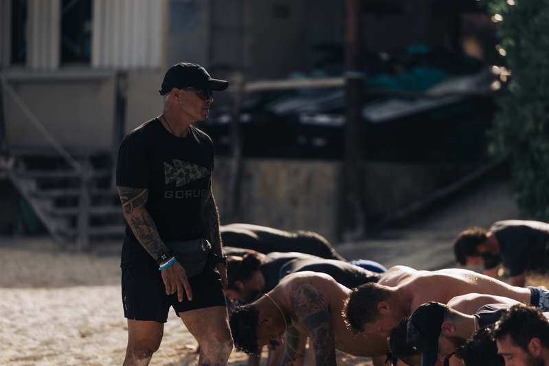 Diverse group of adults and dogs engaged in a relaxed circle exercise at a community park training class